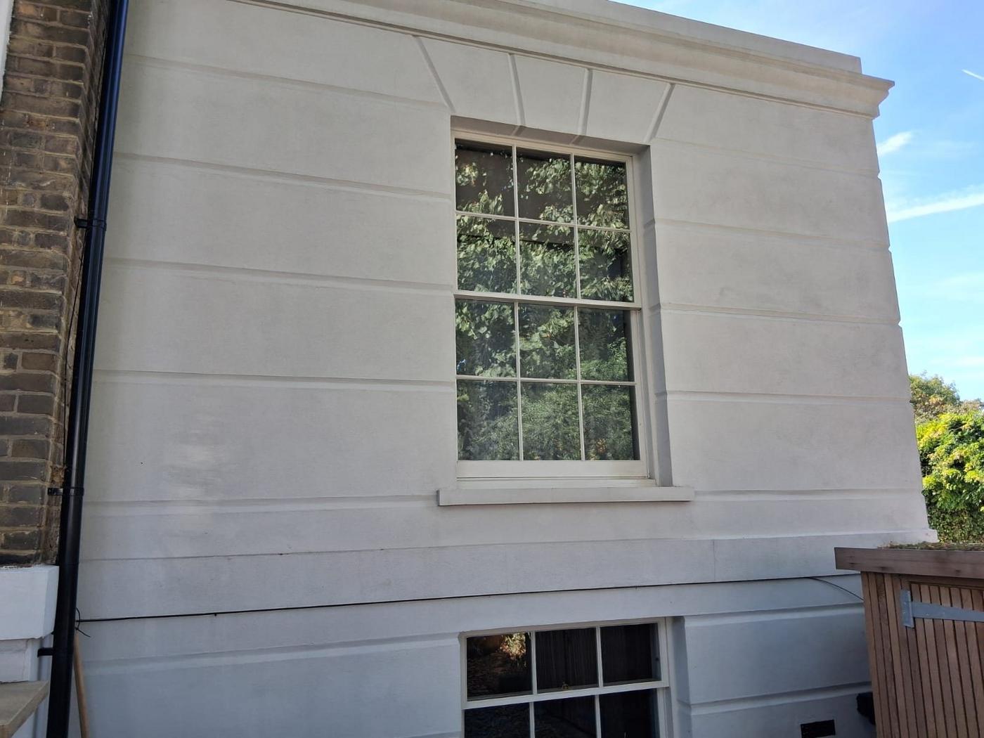 Render on a London townhouse washed back to clean pale stone, with the original sash window