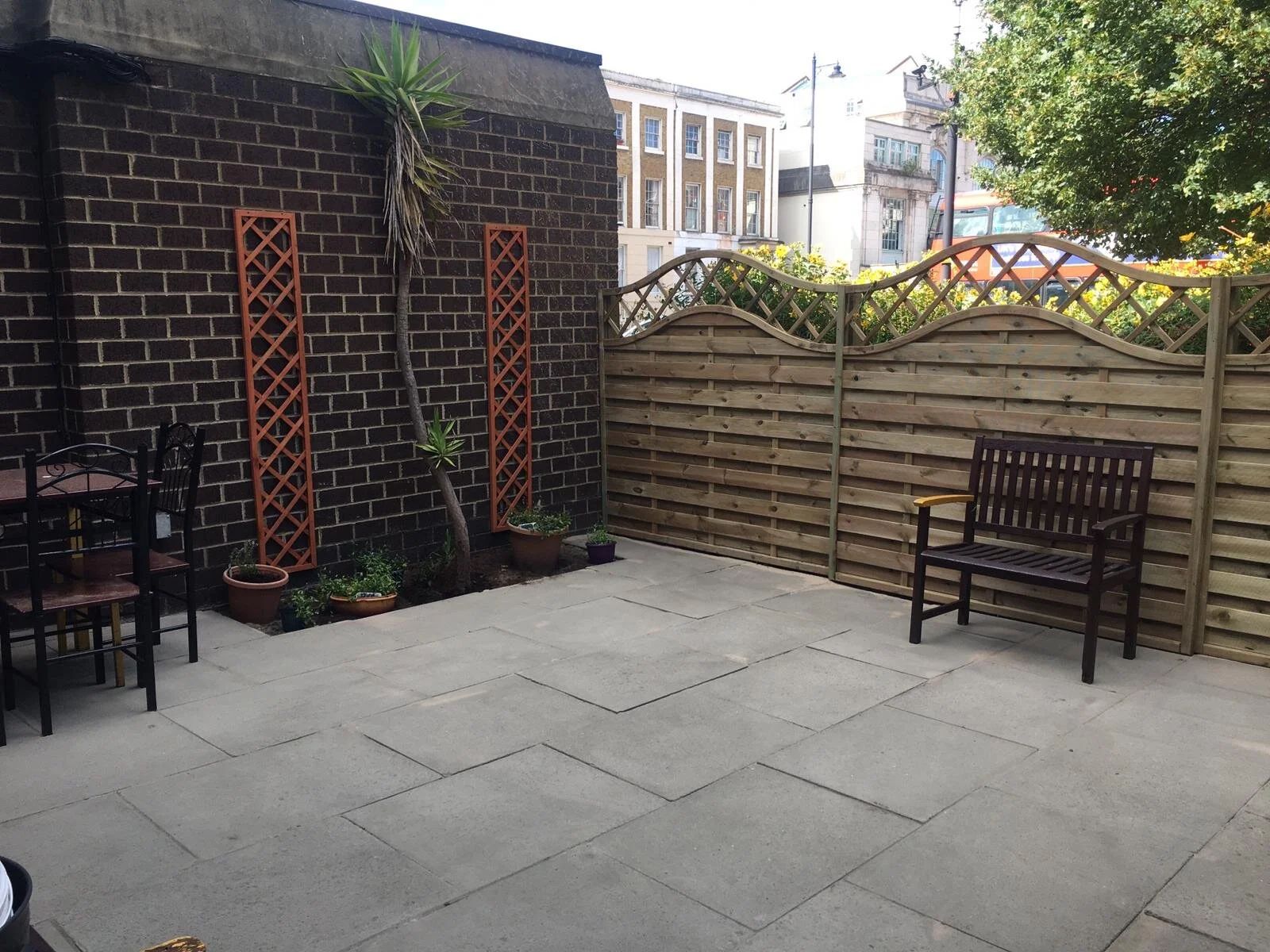 Patio with a bench against a brick wall