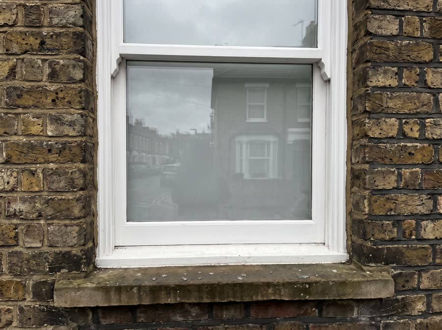 Illustration of a cleaned timber sash window on London stock brick, water drying on the sill